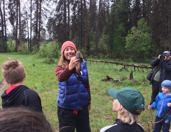 A demonstration during a mini grant workshop outside. Children look on as a demonstrator holds up a bird.